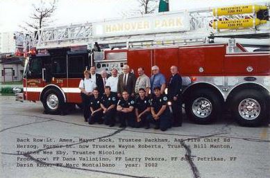 A group of firefighters together in front of fire trucks.
